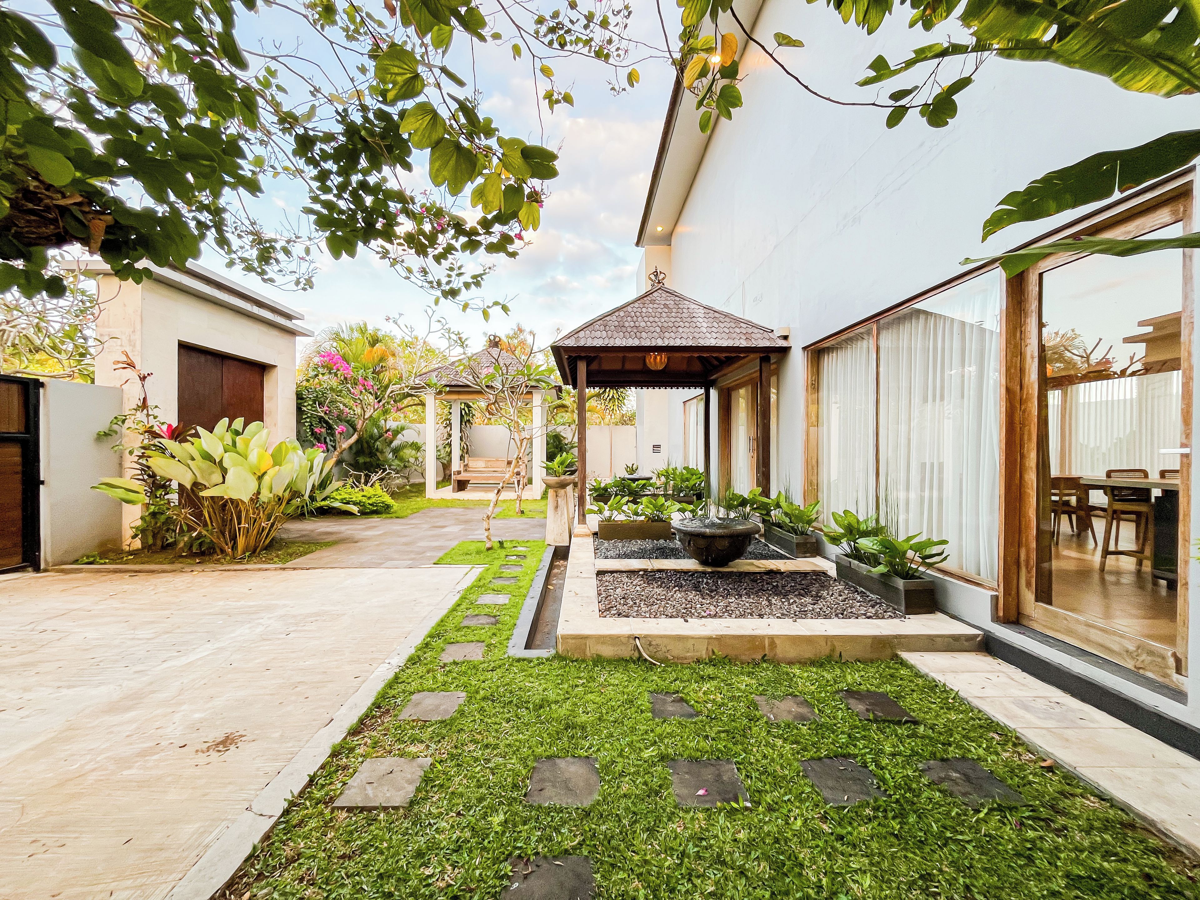 A courtyard with a pergola, potted plants, a water feature, and a seating area.