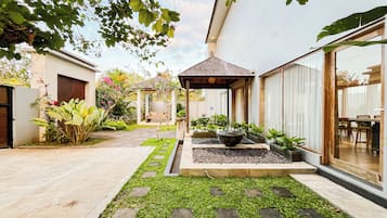 A courtyard with a pergola, potted plants, a water feature, and a seating area.