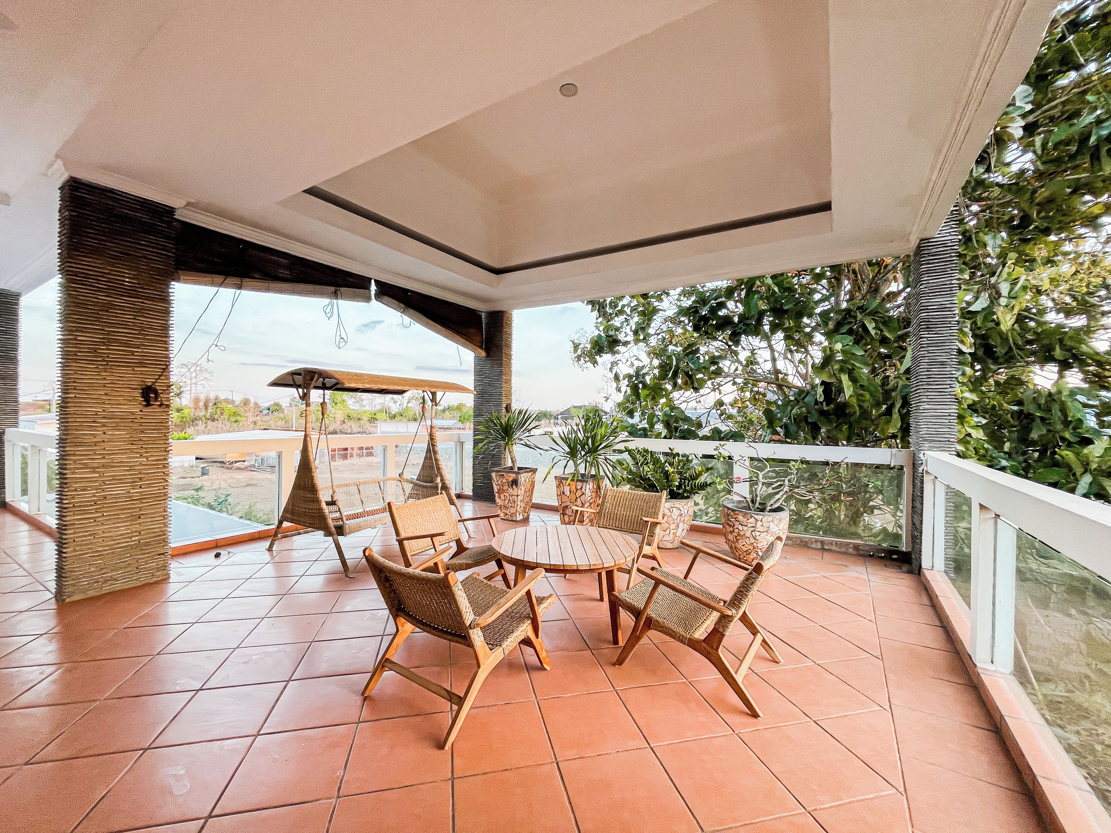 A covered outdoor seating area with wicker furniture and potted plants.