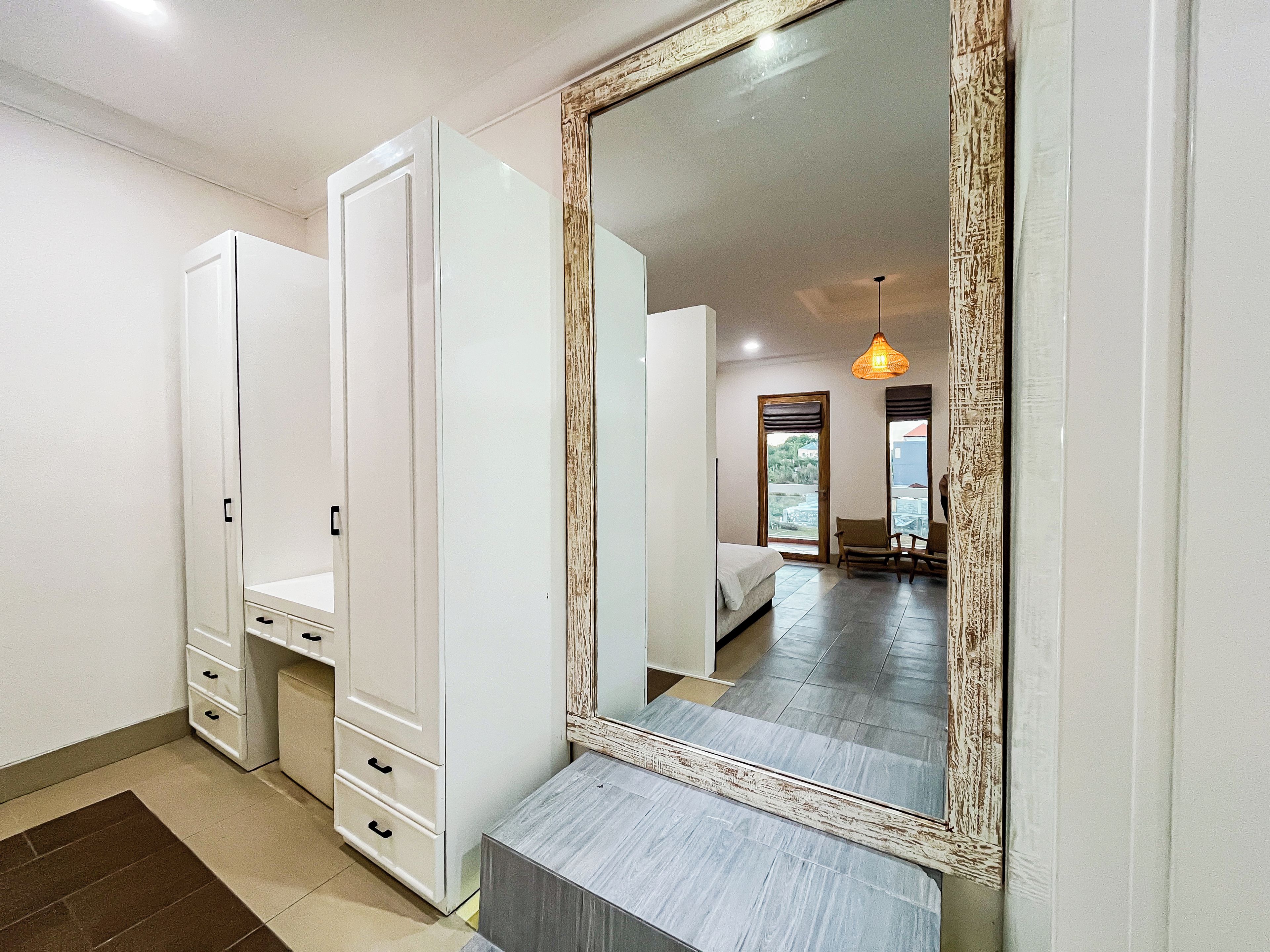 A bedroom with a large mirror, a wardrobe, a bed, and a small table.