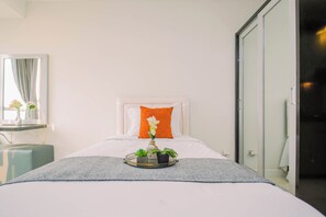 A hotel room with a bed, a bedside table, a mirror, and a window with curtains. - Great Choice Studio At Apartment Cinere Bellevue Suites (Depok)