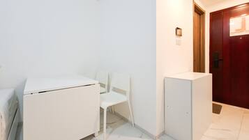 A room with a white desk, a white chair, a white cabinet, and a wooden door.