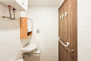 A bathroom with a wooden door, a sink, a mirror, and a towel rack. - Bright And Warm Studio Room At Apartment Sky House Bsd (Tangerang)