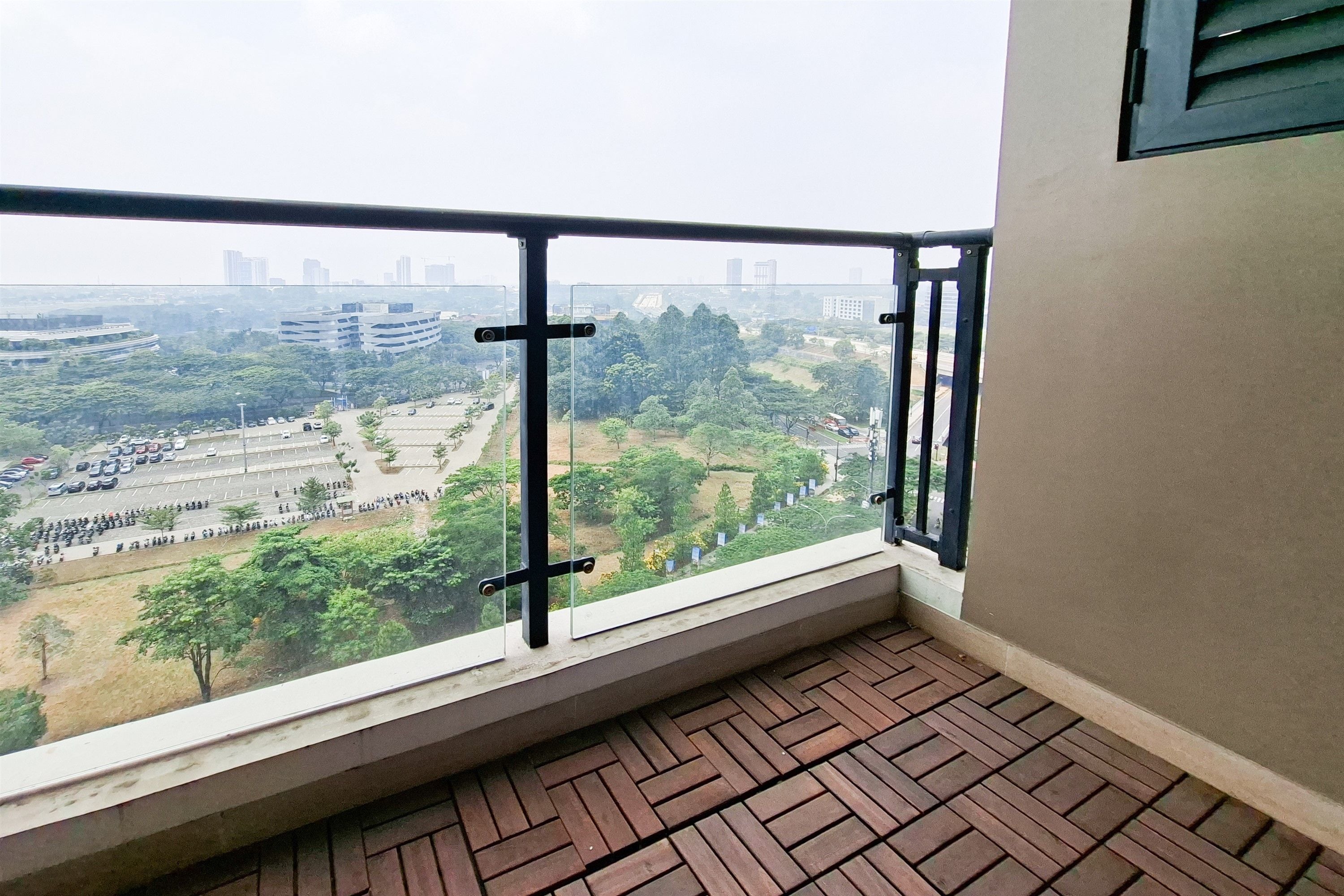 Uma varanda com vista para o horizonte urbano, incluindo edifícios e um estacionamento.