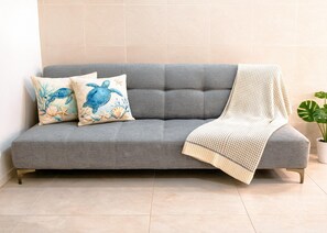 A grey sofa with two decorative pillows, a knitted throw, and a potted plant. - Sleeps 8 in 2 Apartments, 2 Kitchens, WiFi AC, 10 Min Walk to Beach and Market (Playa del Carmen)