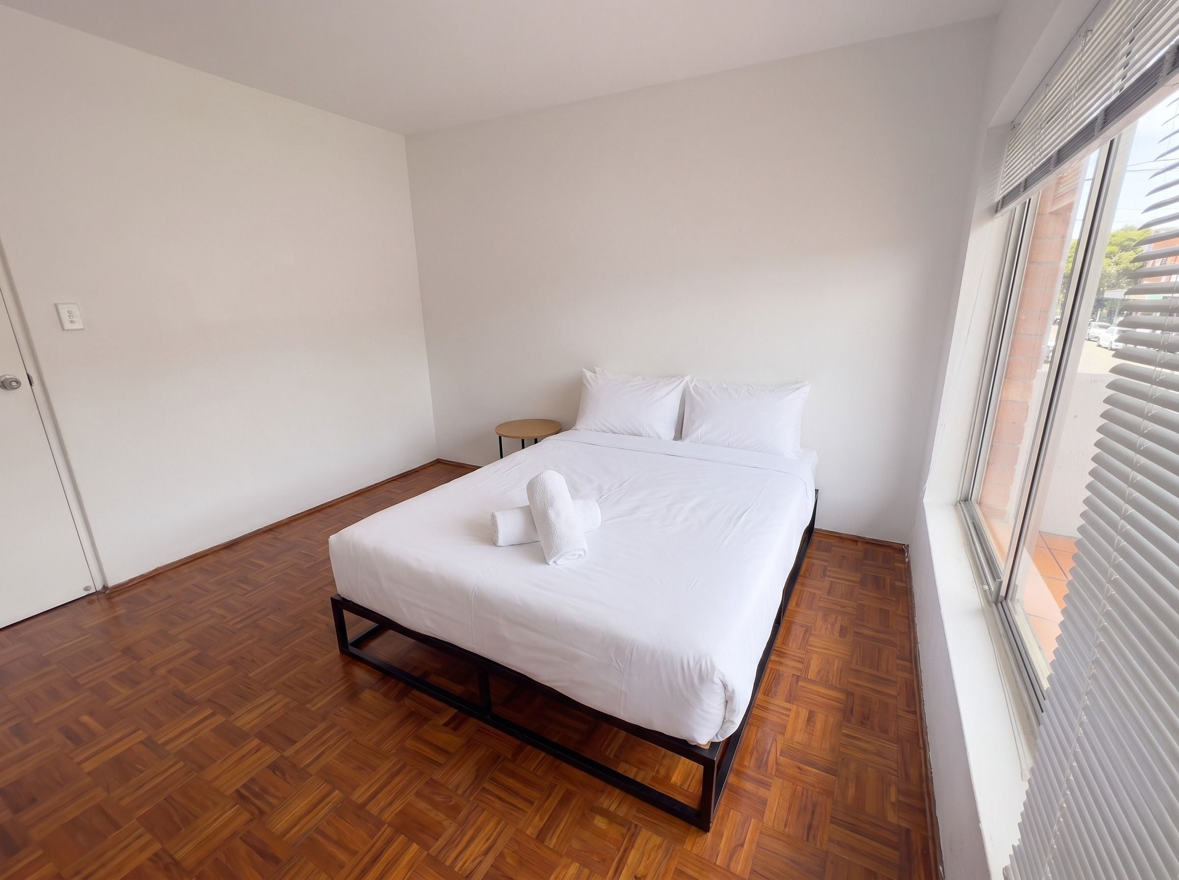 Ein Hotelzimmer mit einem Bett, einem runden Tisch und einem Fenster mit Jalousien.