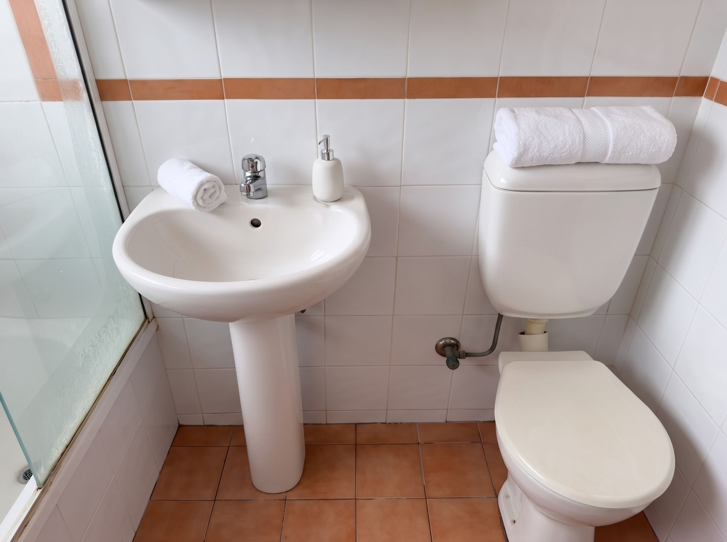 A bathroom with a white sink, a toilet, and a towel on the toilet.