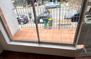 A balcony with a view of a street, a parked car, and a person walking. - Bondi 1BR Apartment, Private Balcony | 2 Min Walk to Beach, Sleeps 4 (Bondi Beach)