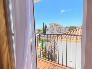 Ein Balkon mit Blick auf eine Wohngegend, darunter Häuser und ein Schwimmbad.