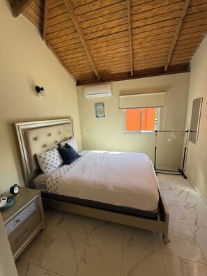 Un dormitorio con cama, mesita de noche y ventana con persianas.