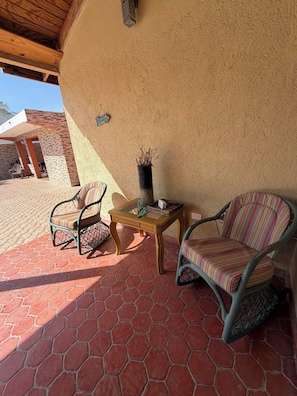 A patio with hexagonal tiles, two wicker chairs, a small wooden table, and a potted plant. - Luxurious 5-bedroom House With Private Pool in Cabrera (Cabrera)