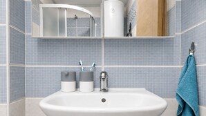 Ein Badezimmer mit einem weißen Waschbecken, zwei Zahnbürstenhaltern, einem Handtuchhalter und einem Spiegel.
