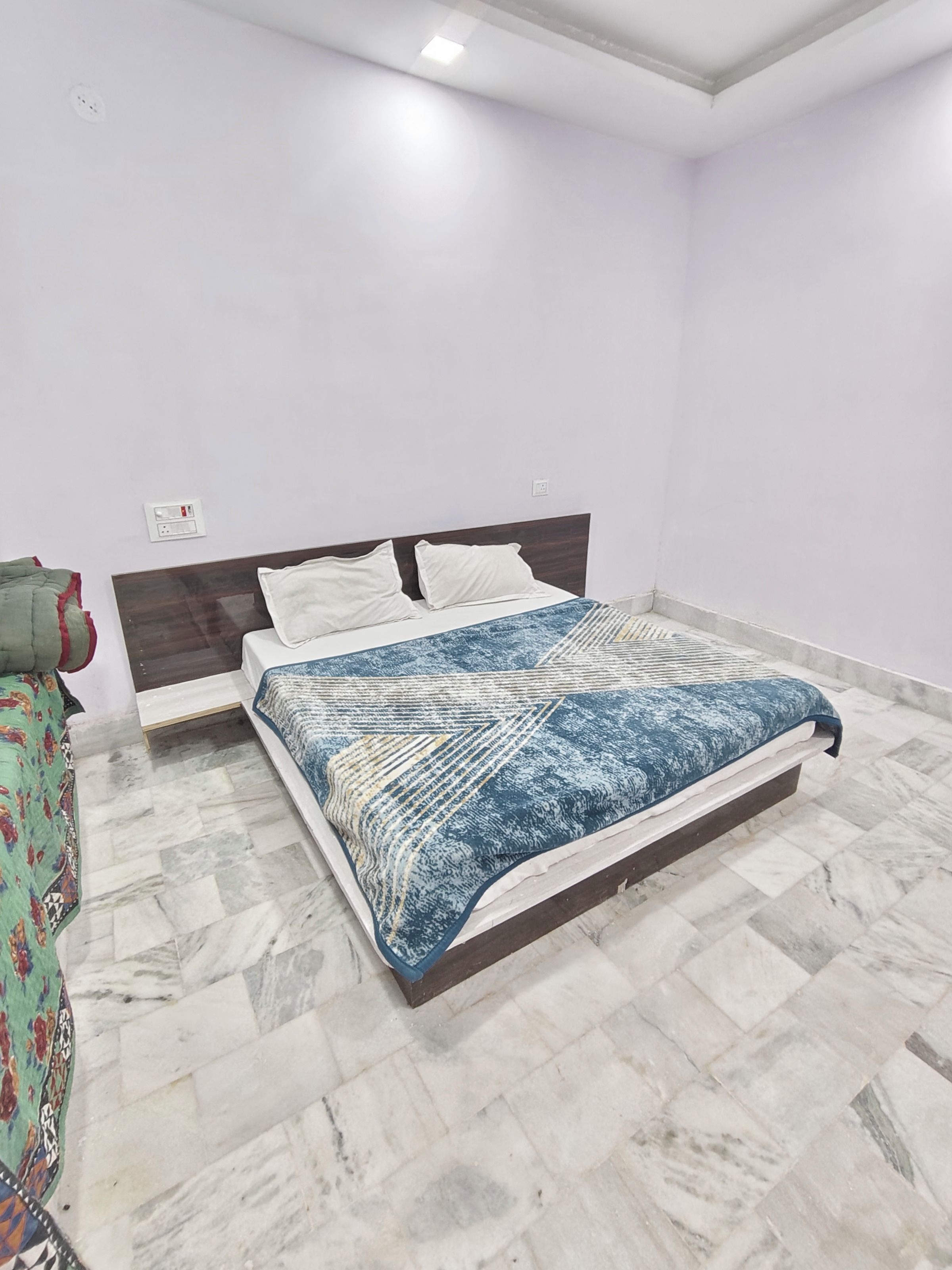 Un dormitorio con una cama, una mesita de noche y un enchufe de pared.