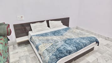Un dormitorio con una cama, una mesita de noche y un enchufe de pared.