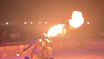 A person performing with fire in a sandy outdoor setting.