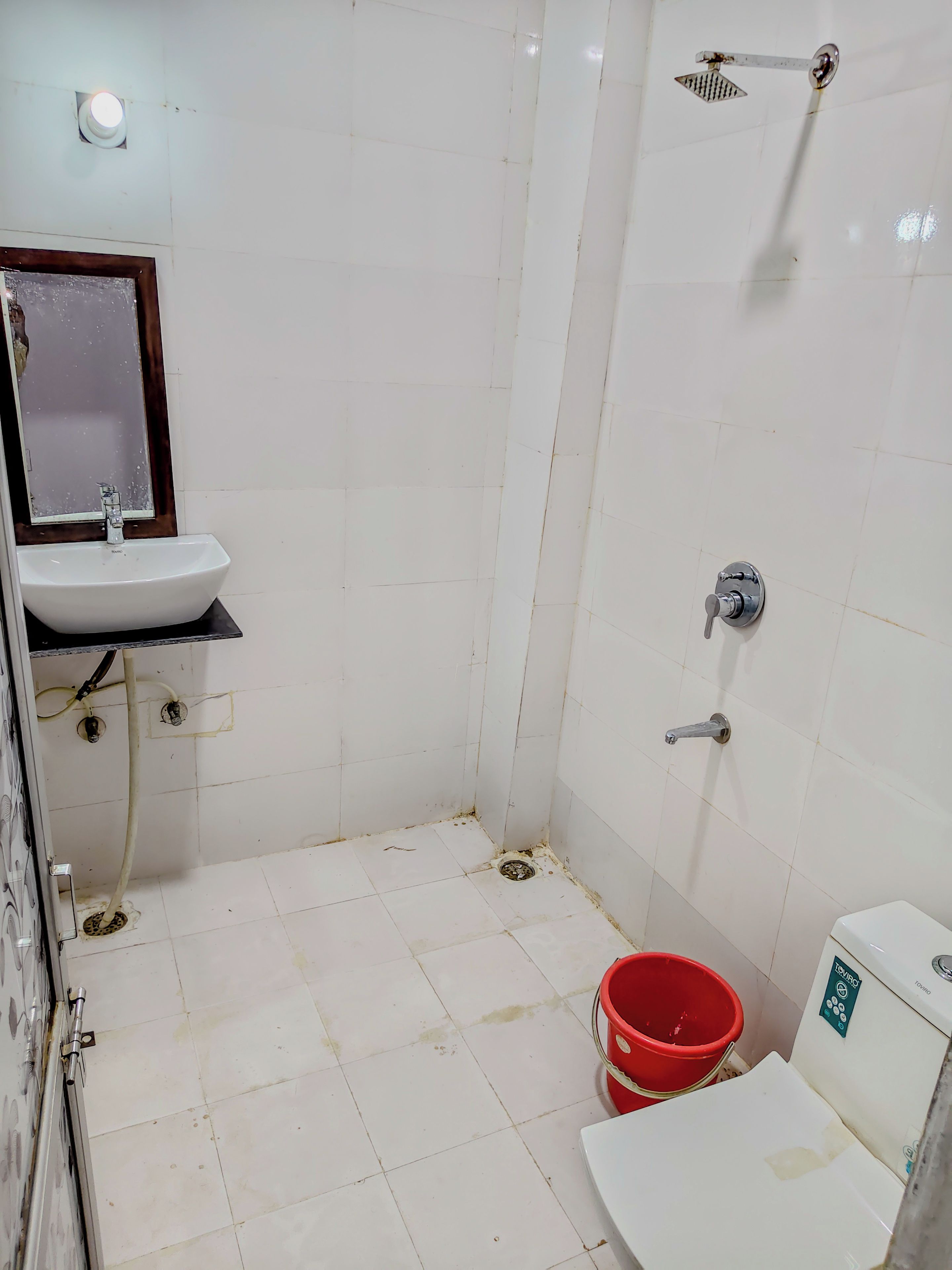 Un baño con lavamanos blanco, espejo, ducha e inodoro.