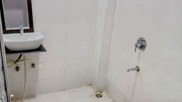 Un baño con lavamanos blanco, espejo, ducha e inodoro.