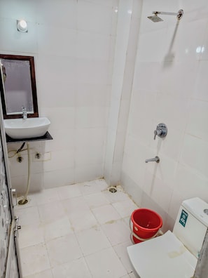 A bathroom with a white sink, a mirror, a shower, and a toilet. - The desert view  (Jaisalmer)