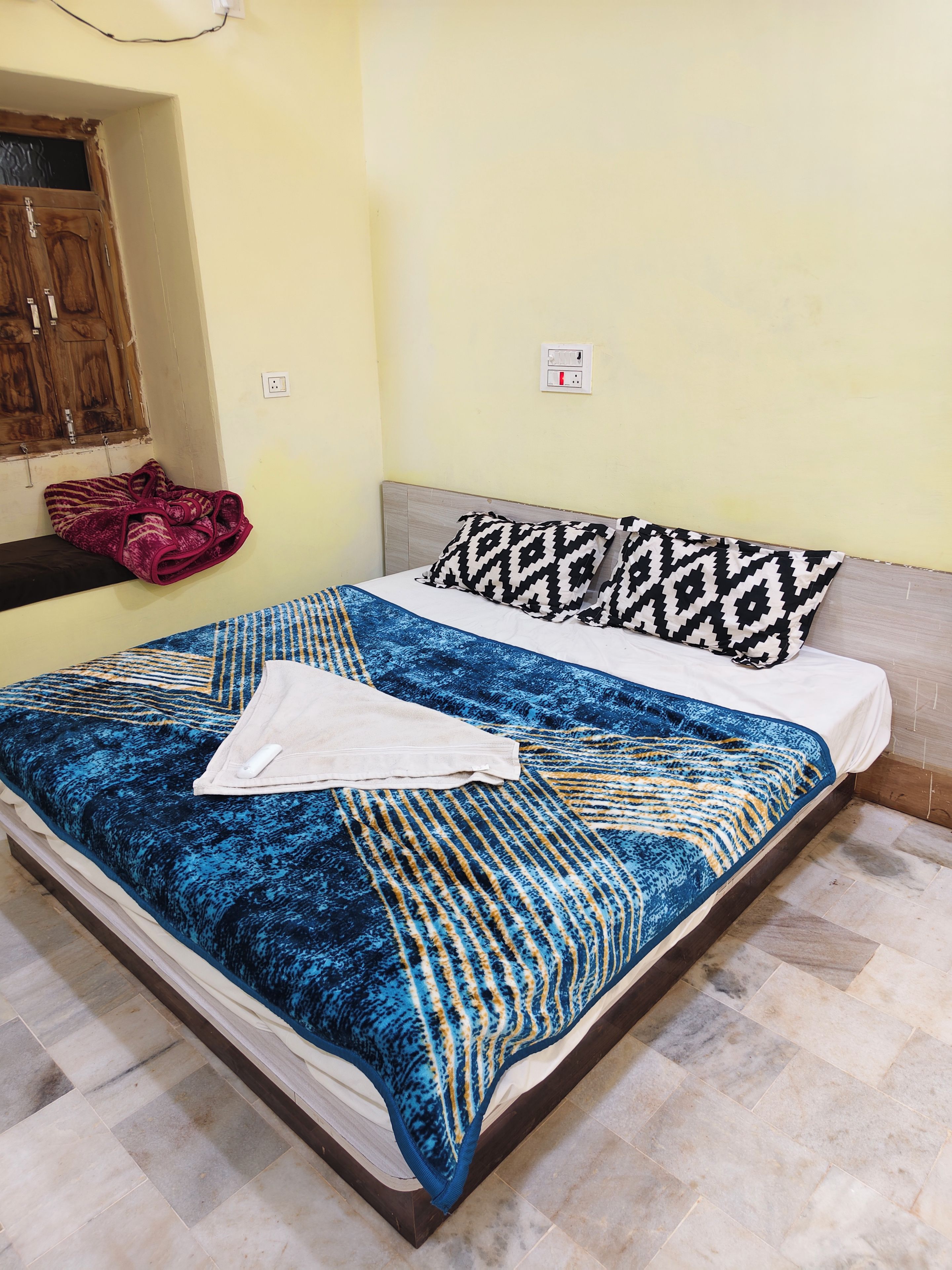 A bed with a patterned bedspread, pillows, and a folded towel.