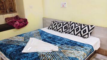 Una cama con colcha estampada, almohadas y una toalla doblada.