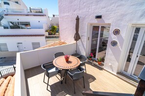 Ein Balkon mit rundem Tisch, vier Stühlen und einem Blumentopf.