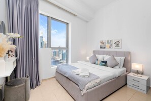 A modern hotel room with a large bed, a view of the cityscape, and a window with curtains. - Sleek 1BR at Dubai Marina (Dubai)