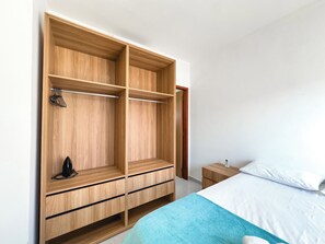 Ein Schlafzimmer mit großem Holzschrank, einem Bett mit weißer Bettwäsche und einem kleinen Nachttisch.