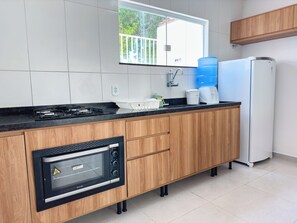 A modern kitchen with a built-in microwave, stove, and sink. - Duplex Apartment 5 with 2 Suites 450m from the Beach in Santa Cruz Cabrália (Santa Cruz Cabrália)