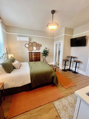 Ein Schlafzimmer mit Bett, Kommode, Schminktisch und Fernseher an der Wand.