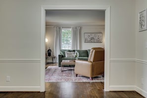 Ein Zimmer mit einem grünen Sofa, einem braunen Sessel und einem gemusterten Teppich.