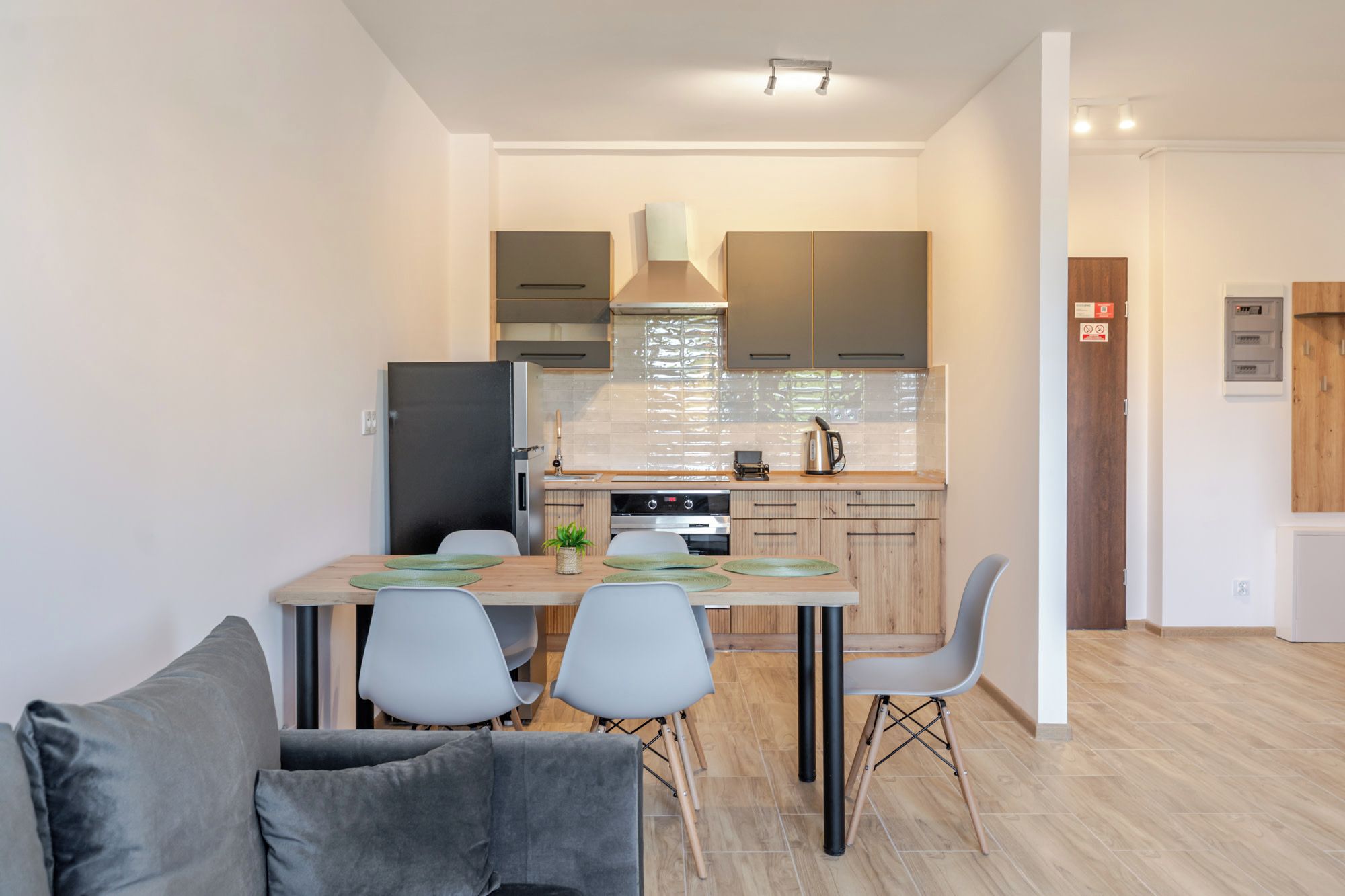 A modern kitchen with a dining area, including a table with chairs, a refrigerator, and a stove.