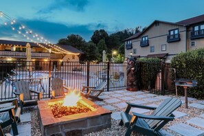 Ein Außenbereich mit einer Terrasse, einem Feuerkorb, Sitzgelegenheiten und einem Pool.