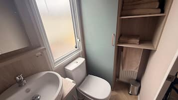 A compact bathroom with a sink, toilet, and a window.