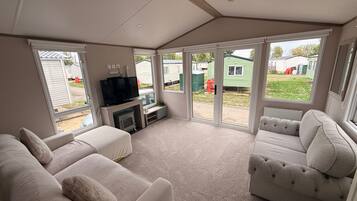 A spacious living area with a fireplace, comfortable seating, and large windows offering views of a residential area.