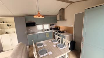 A compact kitchen with a dining area, featuring a wooden table, chairs, and a hanging light fixture.