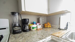 Eine Küche mit Mixer, Kaffeemaschine, Orangenschäler und Schneidebrett.