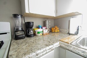 A kitchen with a blender, coffee maker, orange peeler, and a cutting board. - House Sleeps 8 with Air Conditioning (North Little Rock)
