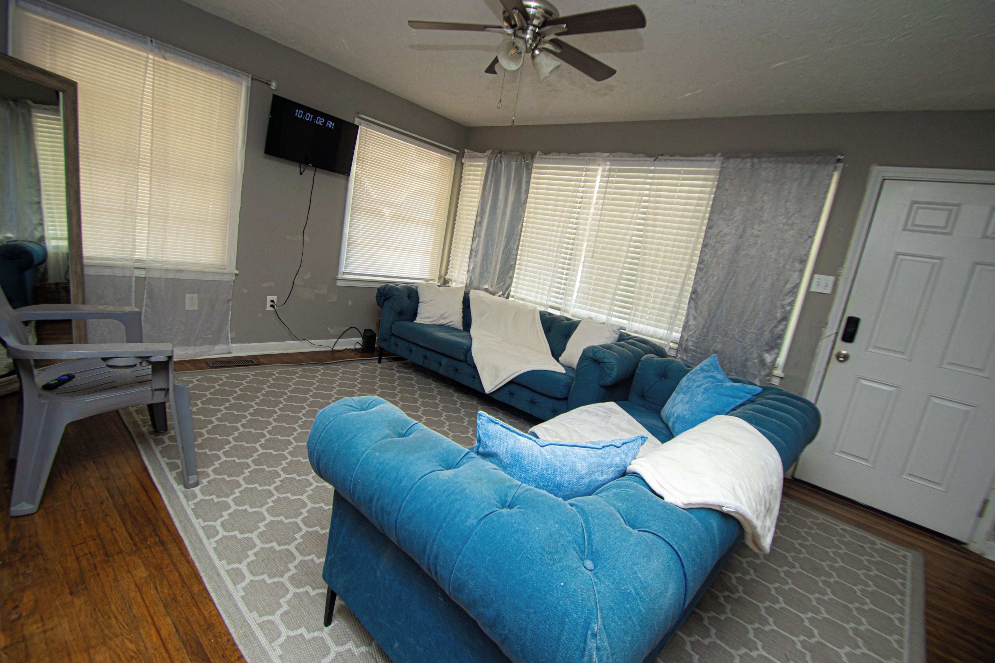 A living room with a blue sofa, a white armchair, and a ceiling fan.