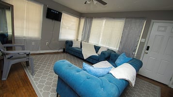 A living room with a blue sofa, a white armchair, and a ceiling fan.