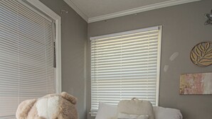 Ein Schlafzimmer mit einem Bett, einem Teddybären und einem Fenster mit Jalousien.