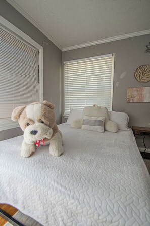 A bedroom with a bed, a teddy bear, and a window with blinds. - House Sleeps 8 with Air Conditioning (North Little Rock)