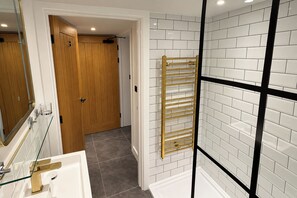 Un baño con cabina de ducha de vidrio, una puerta de madera y un perchero para toallas.