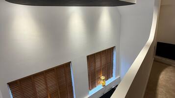 A modern interior with a curved ceiling, recessed lighting, and two windows with wooden shutters.