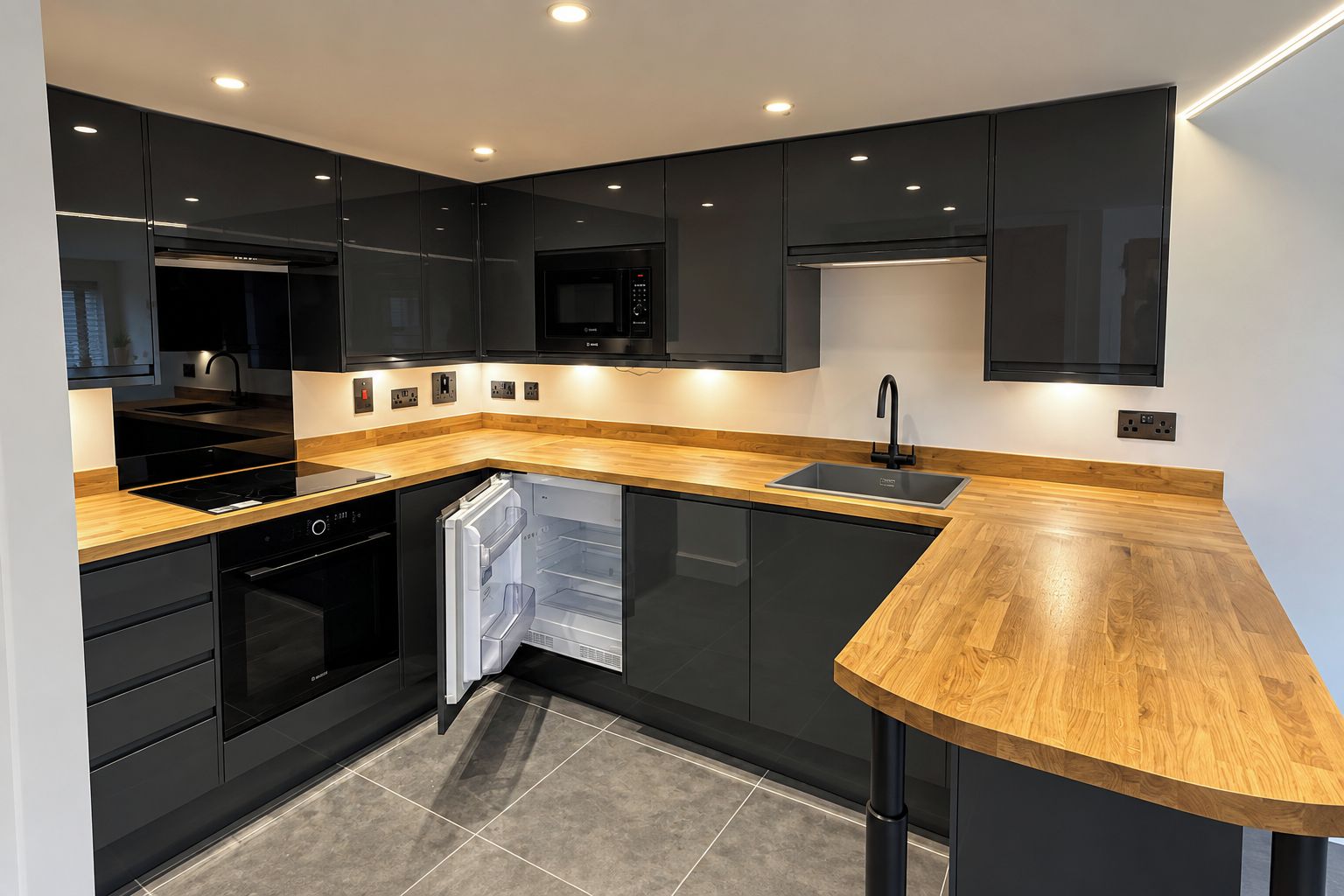 A modern kitchen with black cabinetry, a wooden countertop, and built-in appliances.