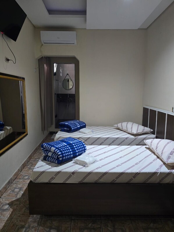A hotel room with two beds, a mirror, an air conditioning unit, and a bathroom with a shower. - Hotel Santos Inn (Santos)