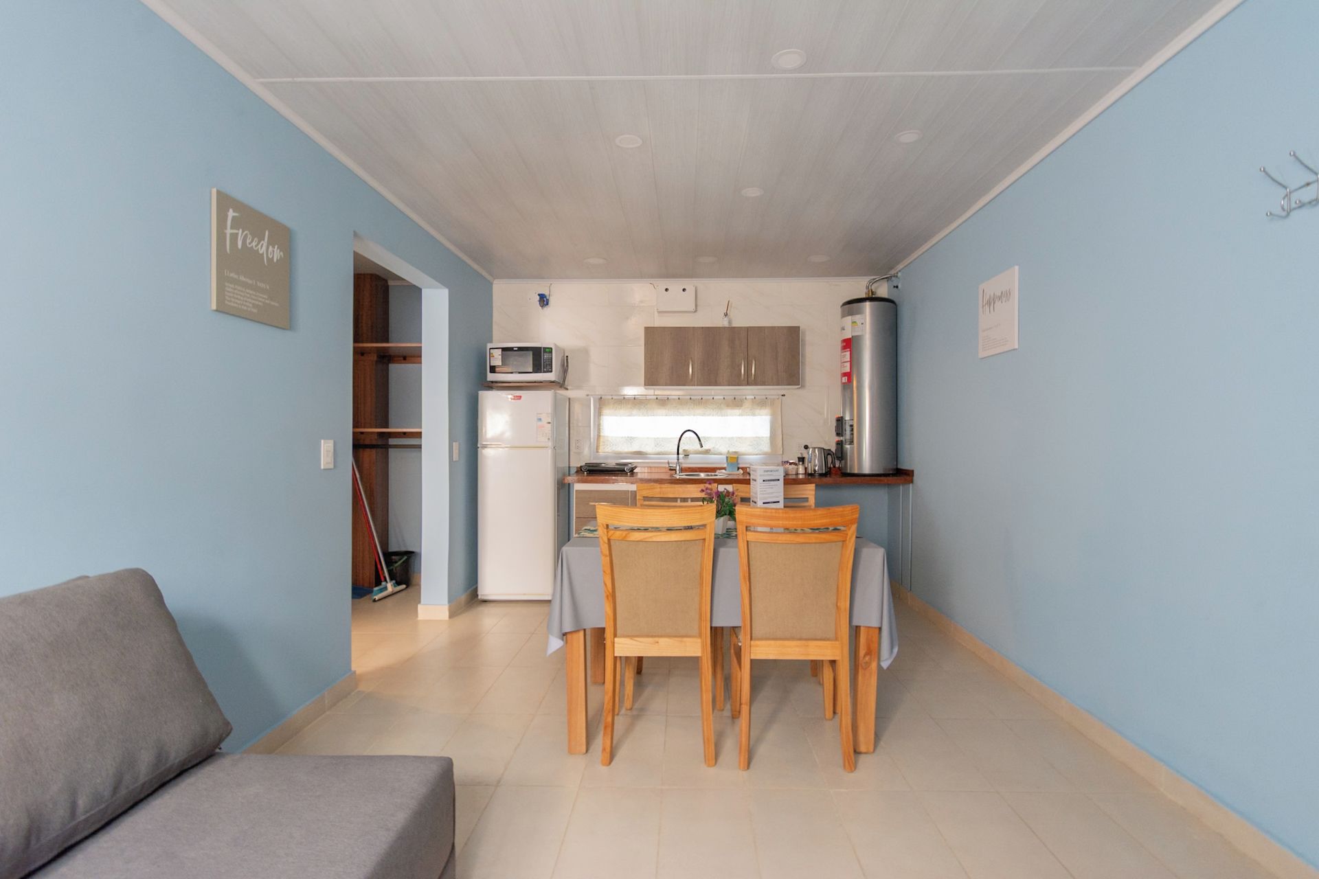 Un espacio habitable compacto con kitchenette, un área de comedor con cuatro sillas y un sofá.