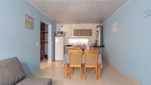 Um espaço compacto com cozinha compacta, área de refeições para quatro pessoas e um sofá.