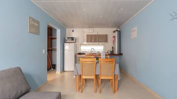 Un espacio habitable compacto con kitchenette, un área de comedor con cuatro sillas y un sofá.