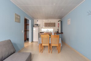 Un espacio habitable compacto con kitchenette, un área de comedor con cuatro sillas y un sofá.