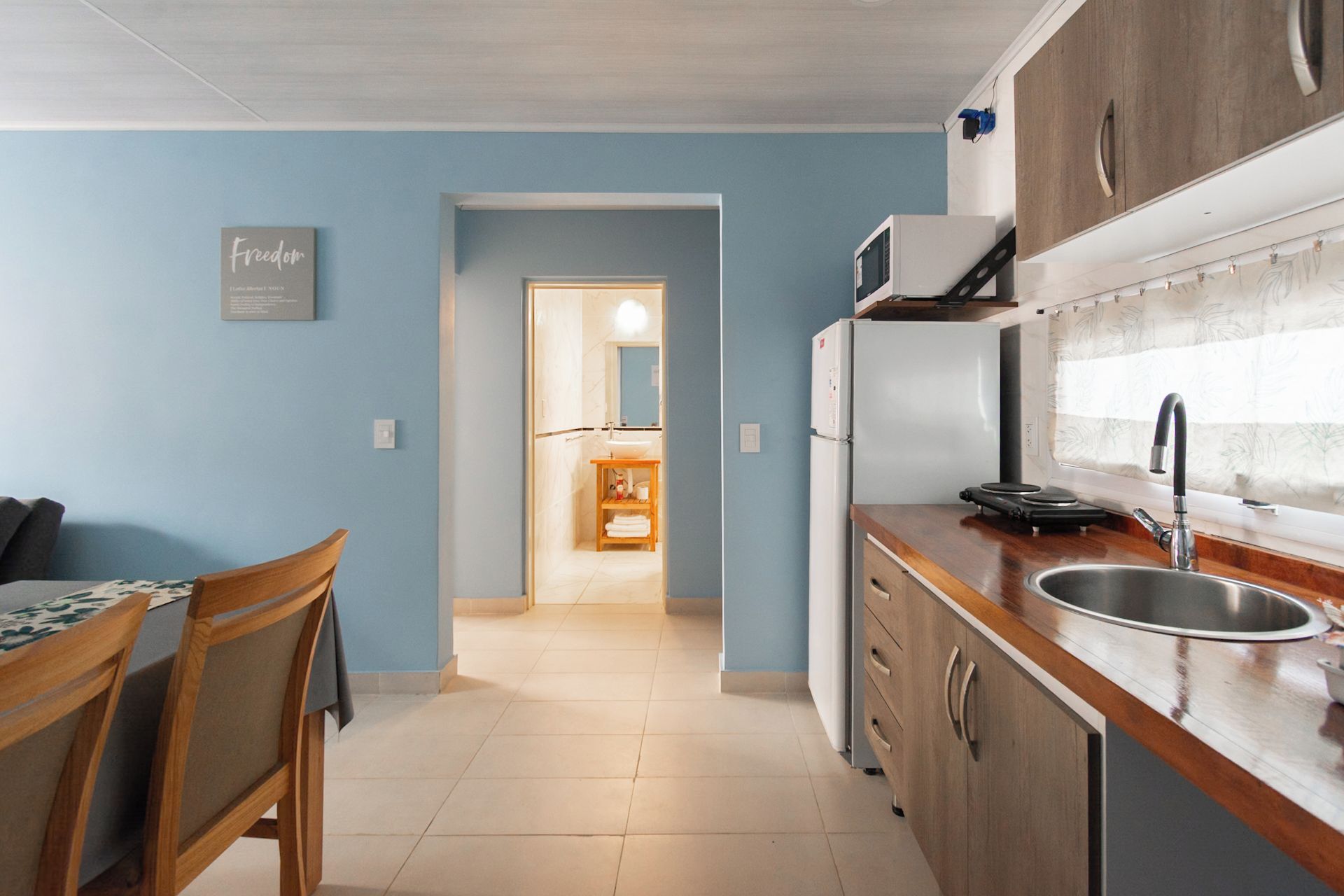 Cocina pequeña con refrigerador, microondas y pileta.